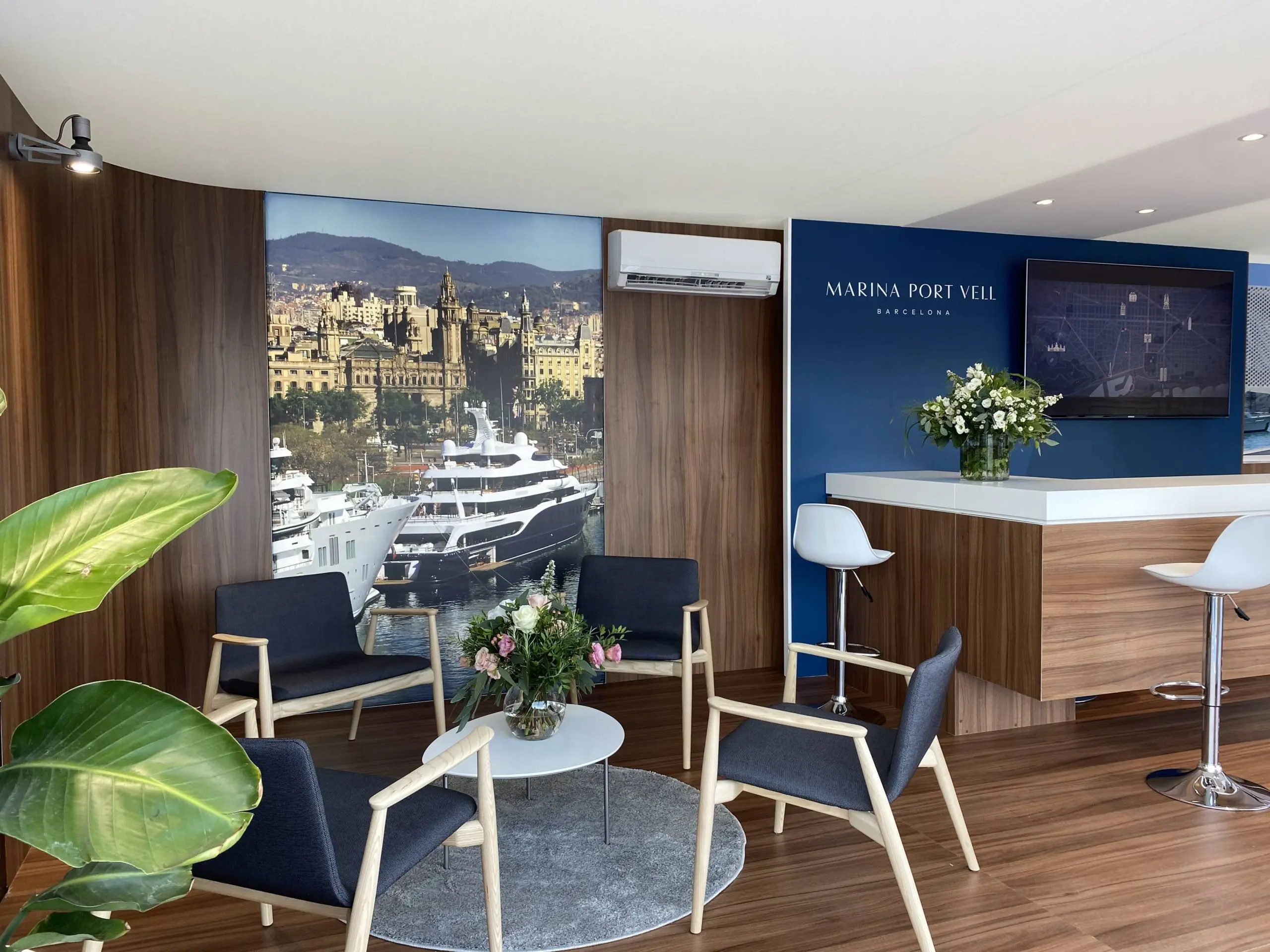 Marina Port Vell reception office with superyacht view, Barcelona cityscape, and branded signage.