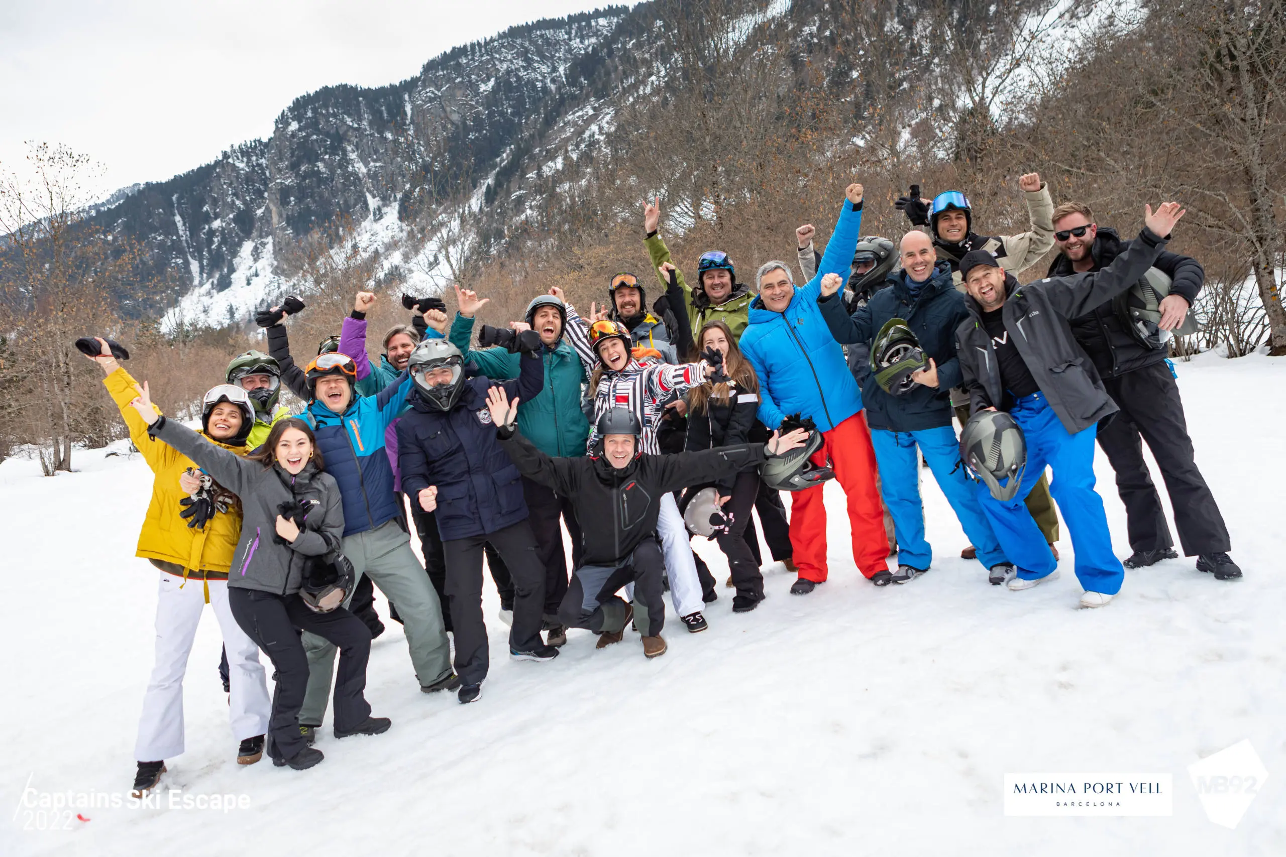 Large group of people in winter clothing posing together on snowy mountain slope.