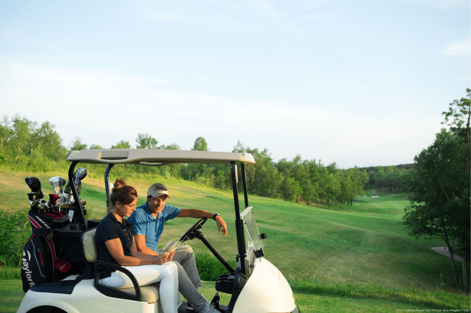 Image of two golfers in a buggy carrying their golf clubs on their way to the next hole.rn